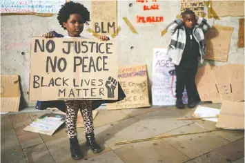  ?? — GETTY IMAGES ?? Children pose in front of discarded placards in Piccadilly Gardens after a Black Lives Matter demonstrat­ion Saturday in Manchester, England. Media outlets are looking for ways of explaining the protests to children.