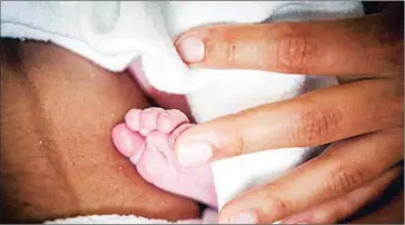  ?? AFP ?? A mother holds her newborn child’s foot. A study published on Wednesday said the ‘birthing girdle’ was likely a part of the ritual of labour and childbirth.