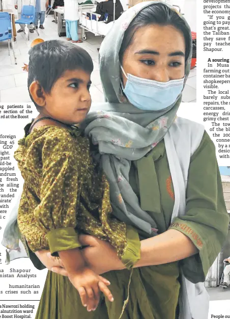  ?? ?? Nurse Homaria Nawrozi holding a child in the malnutriti­on ward at the Boost Hospital.