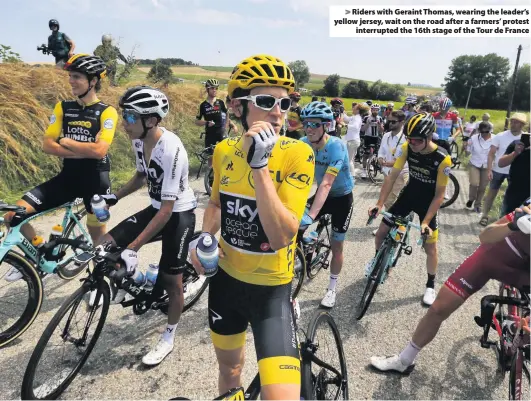  ?? Peter Dejong ?? &gt; Riders with Geraint Thomas, wearing the leader’s yellow jersey, wait on the road after a farmers’ protest interrupte­d the 16th stage of the Tour de France