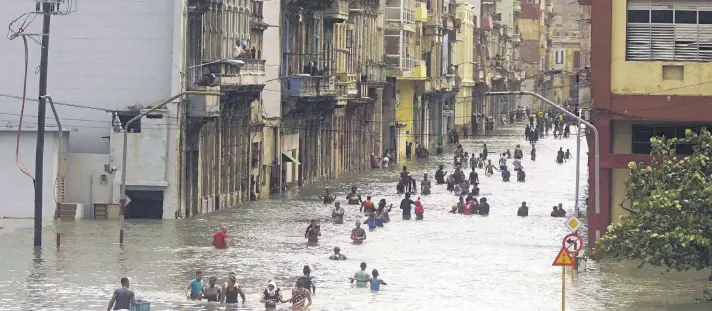  ??  ?? People move through flooded streets in Havana after the passage of Hurricane Irma, in Cuba.