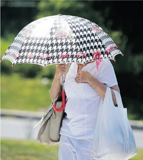  ?? ALLEN MCINNIS / POSTMEDIA NEWS ?? A woman protects herself from the sun. Climate change is listed as one of the biggest threats to mental health.