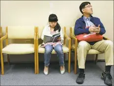  ?? Darrell Sapp/Post-Gazette ?? Karin Hoppo, 9, of Wexford reads a book while she and her father, Toshi, wait to see if Karin has any effects from her oral immunother­apy treatment.