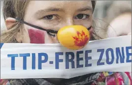  ?? CP PHOTO ?? A woman protests against internatio­nal trade agreements TTIP and CETA in front of EU headquarte­rs in Brussels.