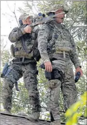  ?? STACEY WESCOTT/TRIBUNE NEWSPAPERS ?? A marksman and a lookout stand on a roof Tuesday during a manhunt after the death of a police officer in Illinois.