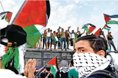  ?? ARIS MESSINIS/AFP ?? Manifestan­tes ondean banderas palestinas y gritan consignas ante la embajada israelí en Atenas, Grecia.
