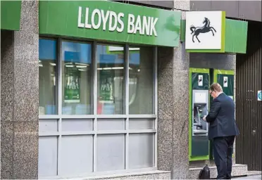  ??  ?? Profitable again: A customer uses ATM outside a Lloyds Bank branch, a unit of Lloyds Banking Group Plc, in London. Its pretax profit was £973mil, compared to a loss of £507mil a year earlier, the London-based bank said in a statement— Bloomberg