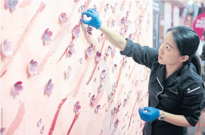  ??  ?? Main photo Janice Wong attaching sugar flowers onto the backdrop at CentralWor­ld.