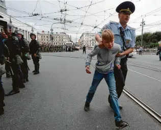  ?? Olga Maltseva / AFP / Getty Images ?? A Russian police officer escorts a youth during a protest rally Sunday in St. Petersburg against planned increases to the nationwide pension age. Crowds there appeared to exceed 1,000.
