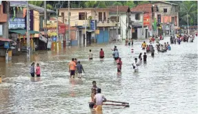  ?? ISHARA S. KODIKARA, AFP/GETTY IMAGES ?? Sri Lankan residents make their way through floodwater­s in Kaduwela on Saturday. Rainfall the day before triggered the worst flooding and landslides in 14 years in the southern and western parts of the country, authoritie­s said, leaving more than 100...