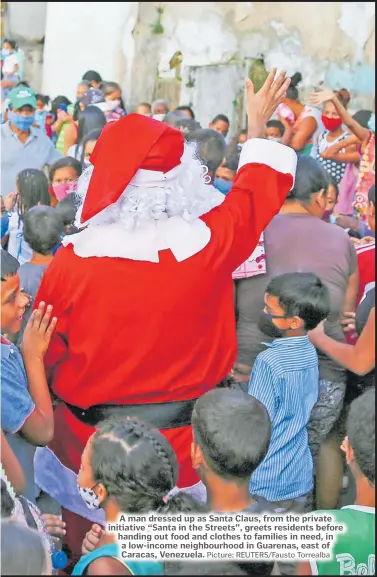  ?? Picture: REUTERS/Fausto Torrealba ?? A man dressed up as Santa Claus, from the private initiative “Santa in the Streets”, greets residents before handing out food and clothes to families in need, in a low-income neighbourh­ood in Guarenas, east of Caracas, Venezuela.