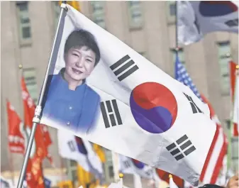  ?? LEE JIN- MAN, AP ?? A South Korean national flag with a picture of impeached South Korean President Park Geun- hye is seen during a rally opposing her impeachmen­t in Seoul on Feb. 25.