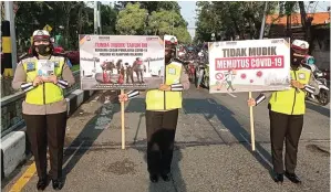  ?? LUDRY PRAYOGA/JAWA POS ?? PATUHI: Anggota Satlantas Polres Gresik menyosiali­sasikan larangan mudik di perempatan jalan kemarin.