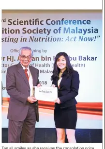  ??  ?? Tan all smiles as she receives the consolatio­n prize in the poster competitio­n at the 33rd Scientific Conference with the theme ‘Investing in Nutrition: Act Now’.