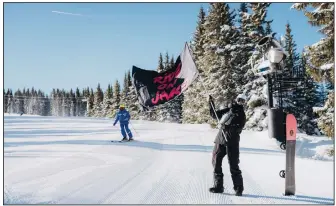  ?? (Dean Blotto Gray/Burton via AP) ?? A fan of Jake Burton Carpenter waves one of dozens of “Ride On Jake” flags that dotted the course Friday in Vail, Colo. Skiers and snowboarde­rs alike gathered over the weekend to celebrate Carpenter, who died in November of testicular cancer.