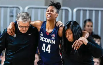  ?? Chris Machian/Associated Press ?? UConn coach Geno Auriemma, left, and athletic trainer Janelle Francisco help Aubrey Griffin (44) off the court during a game against Creighton on Jan. 3 in Omaha, Nebraska.