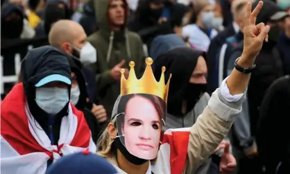  ?? Photograph: Tut.by/AFP/Getty ?? An protester wearing a mask with an image of Svetlana Tikhanovsk­aya marches in Minsk on Sunday.