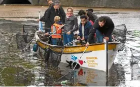  ?? —AFP ?? CRUISE FOR A CAUSE Volunteers use fishing rods to collect plastic from one of Amsterdam’s famous canals. A foundation has organized an event to make the canals plastic-free.