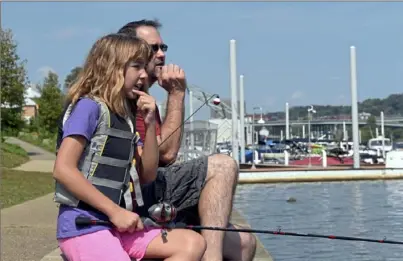  ?? Christian Snyder/ Post- Gazette ?? Megan Haravan and her father, Alan Haravan, wait for a bite during a family fishing event Sunday at South Shore Riverfront Park on the South Side. “Maybe I can learn why she’s always outfishing me,” the fifth grader’s father said.