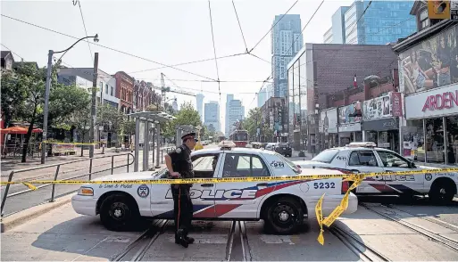  ?? CARLOS OSORIO TORONTO STAR FILE PHOTO ?? July 1 Toronto police block Queen St. W. the morning after a triple shooting that left one woman injured and killed two men.