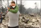  ?? The Associated Press ?? Todd Caughey hugs his daughter, Ella, on Tuesday as they visit the site of their home destroyed by fires in Kenwood, Calif.