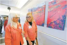  ??  ?? St. Vincent Hospital Auxiliary members Alberta Stanfield, left, and Carol Sidell on Thursday walk past local artwork hanging in the new Frost Pavilion.