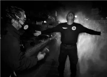  ?? AP Photo/Marco Ugarte ?? In this May 30 file photo, paramedic coordinato­r Oscar Becerril decontamin­ates fellow paramedic Cesar Avila after going out on a night call to pick up a COVID-19 patient, at their base Troya in Iztapalapa, a Mexico City borough.