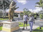  ?? BILL INGRAM / THE PALM BEACH POST ?? Visitors to the 2017 Honda Classic walk past a statue of a bear in front of PGA National Hotel and Spa in Palm Beach Gardens on Saturday.