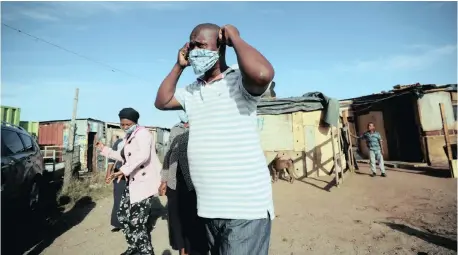  ?? | MIKE HUTCHINGS Reuters ?? A COMMUNITY volunteer dons a face mask as team members prepare to distribute food packages during the national lockdown aimed at limiting the spread of the coronaviru­s disease, Covid-19, in a Cape Town township at the weekend.