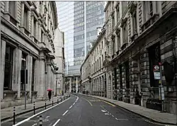  ?? MATT DUNHAM / AP ?? A person walks with an umbrella in light rain Tuesday in the London financial district on the first morning of England entering a third national lockdown since the coronaviru­s outbreak began.