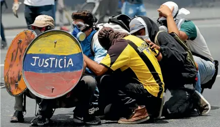  ?? PHOTO: REUTERS ?? Opposition supporters use a shield reading ‘‘Justice’’ as they clash with security forces during a rally against Venezuela’s President Nicolas Maduro in Caracas.