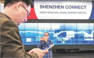  ?? BLOOMBERG ?? Visitors use smartphone­s to take photograph­s under a Shenzhen-Hong Kong Stock Connect sign, following the launch ceremony at the Hong Kong Stock Exchange.