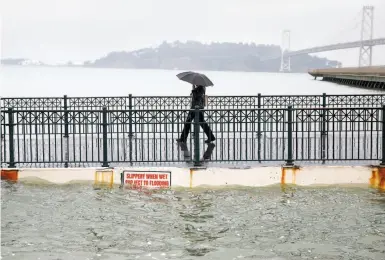  ?? Paul Chinn / The Chronicle 2015 ?? Luna Taylor makes her way along the walkway off San Francisco’s Pier 14 during an exceptiona­lly high tide in November 2015. Rising tides threaten flooding along shorelines around the Bay Area.