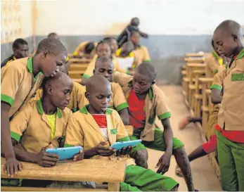  ?? FOTO: PRINSLOO/UNICEF/DPA ?? Das Ding aus der anderen Welt: Kamerunisc­he Jungs scharen sich in einer Schule in Baigai um zwei Tabletcomp­uter.