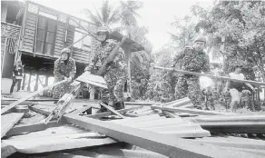  ?? — Gambar Bernama ?? ROSAK: Sepasukan APM Kubang Pasu bertungkus-lumus membersihk­an rumah penduduk yang terjejas akibat puting beliung di Kampung Pida 4 Deli semalam.