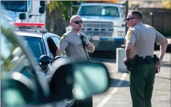  ?? Austin Dave/The Signal ?? (Above) At Wolf’s Towing yard, Santa Clarita Valley Sheriff’s Station deputies guard a vehicle allegedly involved in a Sylmar robbery on Thursday. (Below) A damaged burgandy Nissan Versa sits at the yard. Officers suspect the car was tied to a robbery...