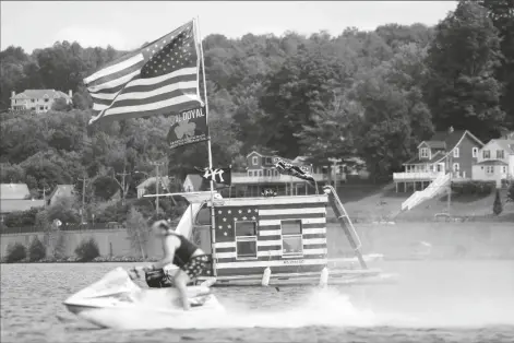  ?? ASSOCIATED PRESS ?? A JET SKIER PASSES A PATRIOTIC SHANTY-BOAT Monday. owned by AJ Crea on Pontoosuc Lake on Labor Day in Pittsfield, Mass., on