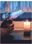  ?? FOTO: FABIAN STRAUCH/DPA ?? Eine Frau betet mit einer eine Kerze an einem Fenster. Jeden Sonntag wollen die Christen in Hückelhove­n jeweils um 18 Uhr ein Licht ans Fenster stellen.