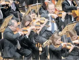  ?? Gina Ferazzi Los Angeles Times ?? VIOLINISTS are in motion during L.A. Philharmon­ic performanc­e Friday at Disney Hall. The program included Esa-Pekka Salonen’s new piece, “Pollux.”