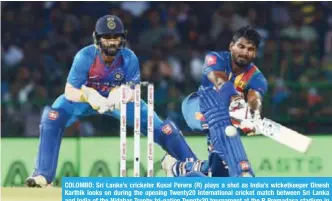  ??  ?? COLOMBO: Sri Lanka’s cricketer Kusal Perera (R) plays a shot as India’s wicketkeep­er Dinesh Karthik looks on during the opening Twenty20 internatio­nal cricket match between Sri Lanka and India of the Nidahas Trophy tri-nation Twenty20 tournament at the...