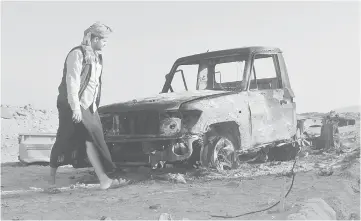  ??  ?? A man walks past a vehicle after an Apache helicopter from a Saudi-led military coalition fired a missile at it outside Aden Internatio­nal Airport, Yemen. — Reuters photo