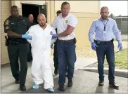  ?? KIMBERLY C. MOORE/THE LEDGER VIA AP ?? Quadruple murder suspect Bryan Riley is led from the Polk County Sheriff’s Office in Lakeland, Fla., on Sunday by Deputy Steve Neil, left, Captain Bart Davis and Detective Brett Bulman.