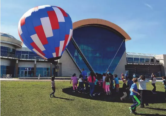  ?? JIM THOMPSON/JOURNAL ?? Students from Colinas del Norte Elementary School in Rio Rancho try to stay in the shadow of a remote-controlled hot-air balloon. It is used for demonstrat­ions at the Anderson-Abruzzo Albuquerqu­e Internatio­nal Balloon Museum.