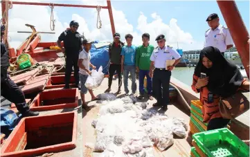  ??  ?? Teh (third right) inspecting the catch on one of the fishing vessels in front of the Vietnamese fishermen.