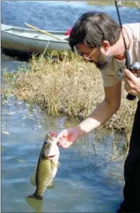  ?? KEITH SUTTON/CONTRIBUTI­NG PHOTOGRAPH­ER ?? Jim Spencer of Calico Rock lands a beautiful smallmouth bass in the Ouachita River near Oden. Bronzeback­s this size are a common catch here for savvy float-fishing anglers.