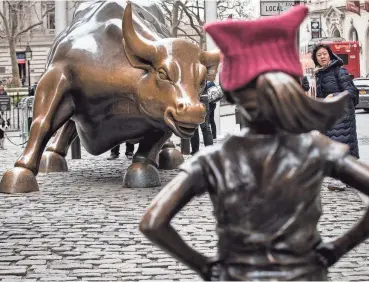  ?? DREW ANGERER/GETTY IMAGES ?? “The Fearless Girl” statue, pictured on March 8, 2017, stood across from the iconic Wall Street charging bull statue for more than a year before it was relocated. State Street Global Advisors, the world’s third-largest asset manager, installed the statue as part of a campaign to pressure companies to add more women to their boards.