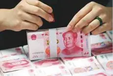  ?? Rex Features ?? A clerk counts yuan banknotes at a bank in Huaibei. A gauge of expected price swings in developing-nations exchange rates is near the lowest since 2014, unruffled by turmoil in the US and Brazil, and concern over China’s growing debt pile.