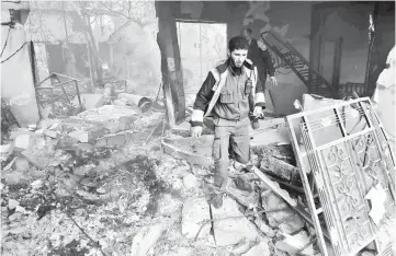  ??  ?? A member of the Syrian Civil Defence, known as the ‘White Helmets’, walks on the rubble of a building as they try to extinguish the flames following an air raid on the rebel-held besieged town of Harasta, in the Eastern Ghouta region on the outskirts...