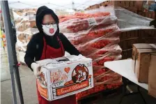  ?? NANCY LANE / HERALD STAFF ?? HOW SWEET (POTATO) IT IT! Salvation Army volunteer Edith Zavala carries a box of sweet potatoes before giving them away on Monday in Chelsea.
