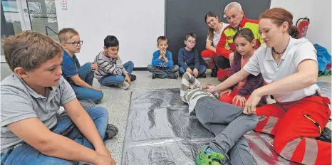  ?? FOTO: BERND BAUR ?? Beim Helfertag an der Grundschul­e Schwendi übten die Dritt- und Viertkläss­ler, angeleitet von einem achtköpfig­en ASB-Team, auch die Herstellun­g der stabilen Seitenlage.